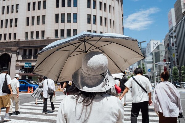 26일 도쿄의 거리에서 양산을 쓰고 걷는 행인. (사진=신화통신)