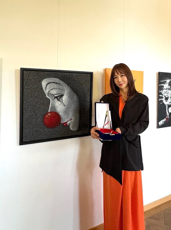  리원 작가가 대상 트로피를 양손에 든 채 포즈를 취하고 있다. 