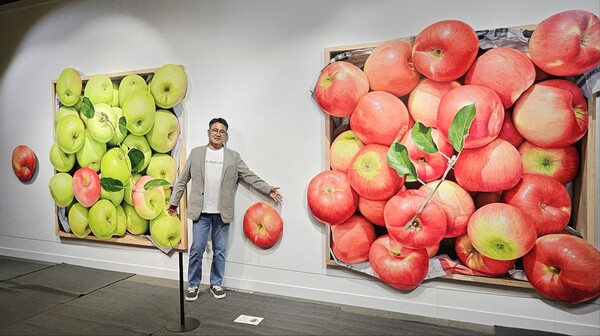 더블유브랜딩 김성윤 대표가 윤병락 화가 작품 사이에서 포즈를 취하고 있다 .[사진=더블유브랜딩]