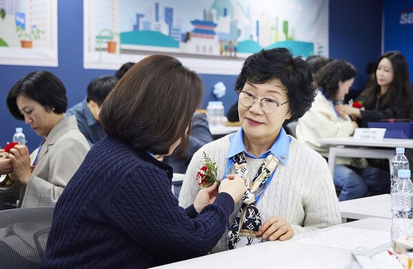 SBI저축은행이 5월 9일 진행한 가족 초청 행사 '부모님 오신데이(Day)'에서 직원들이 부모님께 카네이션을 달아드리고 있다. [사진=SBI저축은행]