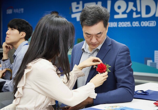 SBI저축은행이 5월 9일 진행한 가족 초청 행사 '부모님 오신데이(Day)'에서 직원들이 부모님께 카네이션을 달아드리고 있다. [사진=SBI저축은행]