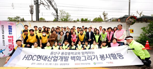 HDC현대산업개발은 5월 15일 도시정비부문 임직원과 용산구 주민, 용강중학교 학생 등 40여 명과 함께 서울시 용산구 용강중학교 일대 담장 벽화그리기 봉사활동을 진행했다. (사진 앞에서 두 번째 줄 오른쪽 다섯 번째부터) 권충환 용강중학교장, 강경민 HDC현대산업개발 도시정비부문장, 박희영 용산구청장. [사진=HDC현대산업개발]